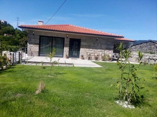 a small stone house with a grass yard at casa do mestre in Vieira do Minho