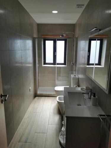 a bathroom with two sinks and a toilet and two windows at casa do mestre in Vieira do Minho