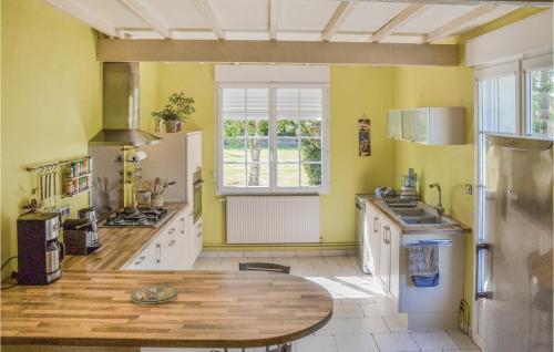 a kitchen with yellow walls and a wooden table at Stunning Home In Montreuil Bellay With 3 Bedrooms, Outdoor Swimming Pool And Heated Swimming Pool in Méron