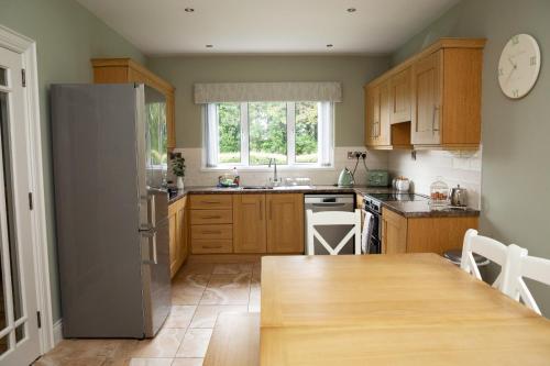 cocina con armarios de madera, mesa y ventana en Patsy’s Corner Cottage en Enniskillen