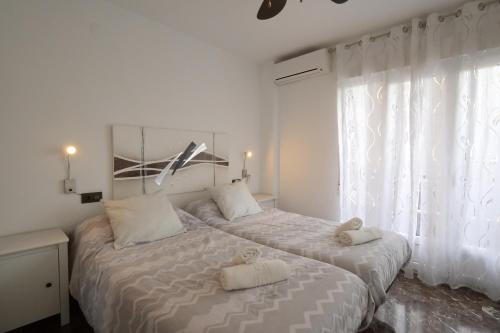 Un dormitorio blanco con una cama con dos toallas encima. en Apartamento Castillo, en Granada