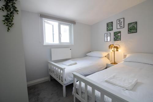 a white bedroom with two beds and a window at The Terrace on Torquay Harbour in Torquay