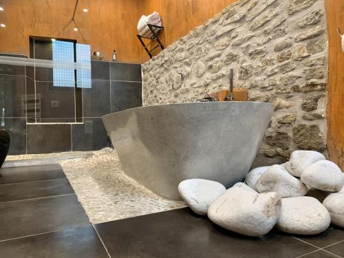 a bathroom with a stone wall and a bath tub at Palais Aoma, hôtel particulier de luxe en Provence in LʼIsle-sur-la-Sorgue