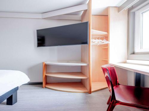 a bedroom with a tv and a bed and a chair at ibis Toulouse Université in Toulouse