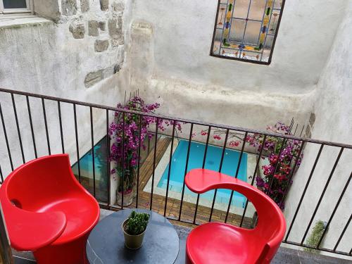 two red chairs and a table on a balcony at Palais Aoma, hôtel particulier de luxe en Provence in LʼIsle-sur-la-Sorgue