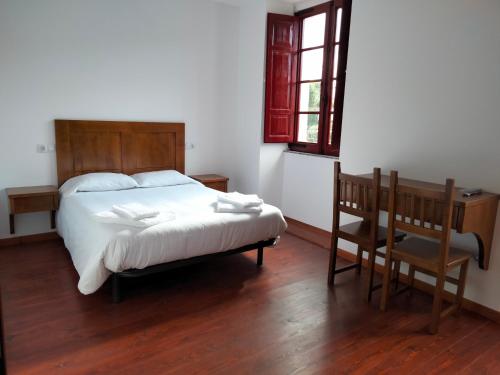 Schlafzimmer mit einem Bett, einem Schreibtisch und einem Stuhl in der Unterkunft Albergue Abeiro do Sor in Mañón