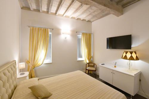 a bedroom with a bed and a desk and a tv at Palazzo degli Stemmi in Todi