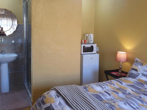 a bedroom with a bed and a sink and a microwave at The Loft Lynette's in Krugersdorp