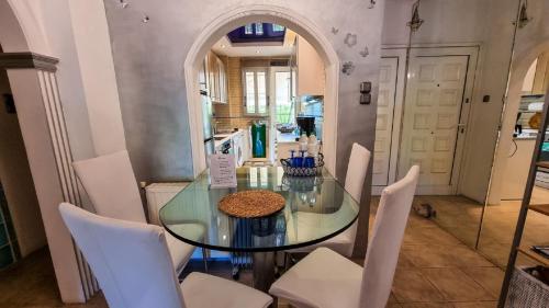 ein Esszimmer mit einem Glastisch und weißen Stühlen in der Unterkunft South Coast Voula Beach Sea RIVIERA Suite in Athen