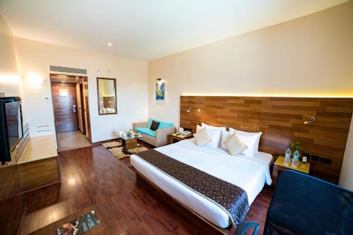 a hotel room with a large bed and a couch at The Orchid Hotel Hinjewadi Pune in Pune