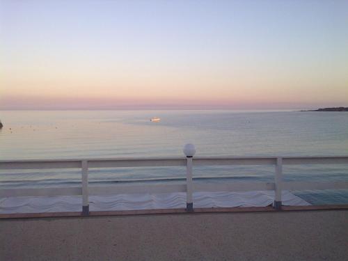a sunset over the ocean with a white fence at Sweet Home & Apartments in Fontane Bianche
