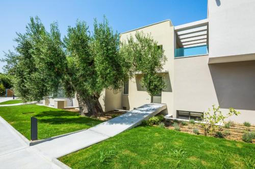 a house with a tree in the yard at Dionisos Luxury Villas in Pefkohori