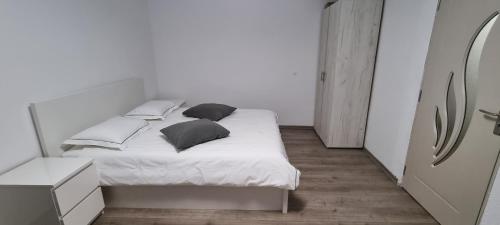 ein weißes Schlafzimmer mit einem Bett mit schwarzen Kissen in der Unterkunft Apartament L & L in Deva