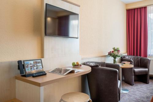 Schlossberghotel Oberhof في أوبرهوف: غرفة في الفندق مع مكتب مع جهاز كمبيوتر وكراسي
