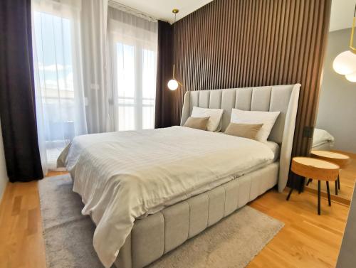 a bedroom with a large white bed and a table at Design Apartment at CITY QUART in Podgorica
