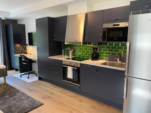 a kitchen with black cabinets and a sink and a refrigerator at Magnolia House Norrviken in Sollentuna