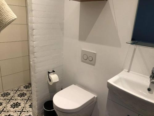 a white bathroom with a toilet and a sink at Tøndegården 2 rooms apartment in Odense