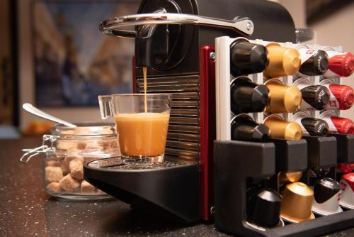 a coffee maker with a glass of juice next to a rack of wine bottles at Luxury cosy family nest in the medieval town in Dinan
