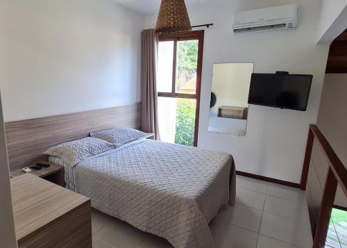 1 dormitorio con 2 camas, TV y ventana en Flat no bosque da praia Pipa-RN, en Pipa