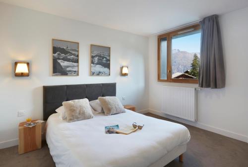 a bedroom with a large white bed with a window at Résidence Néméa Le Hameau - Les Deux Alpes in Les Deux Alpes