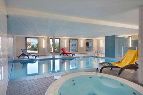 une grande piscine dans un hôtel avec deux chaises dans l'établissement Résidence Néméa Le Hameau - Les Deux Alpes, à Les Deux Alpes