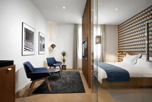 ベオグラードにあるDominic Smart & Luxury Suites - Editionのベッドと椅子付きのホテルルーム