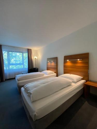una camera d'albergo con tre letti e una finestra di City Hotel Fortuna Reutlingen a Reutlingen