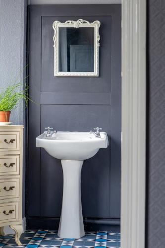 a bathroom with a white sink and a mirror at The Bear Bread Bakery B&B, Ensuite rooms above the Bakery, Colyton in Colyton