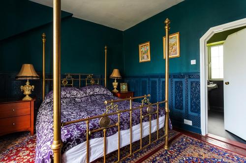 una camera con letto a baldacchino e pareti blu di The Bear Bread Bakery, boutique en-suite rooms with breakfast in the Bakery, in the heart of Colyton a Colyton