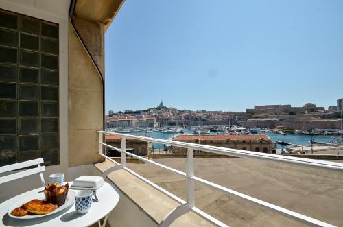 une table avec une assiette de nourriture sur un balcon dans l'établissement MASSILIA BLUE - Grand appartement refait à neuf avec vue sur le Vieux Port, à Marseille