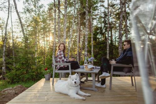 a man and woman sitting at a table with a dog at Glamping Julared in Mullsjö