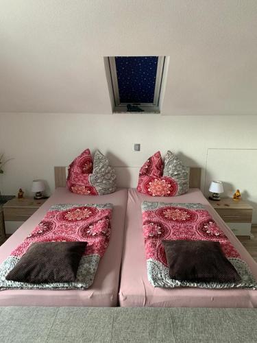 two beds in a bedroom with pink sheets and pillows at FeWo Weitblick in Singen
