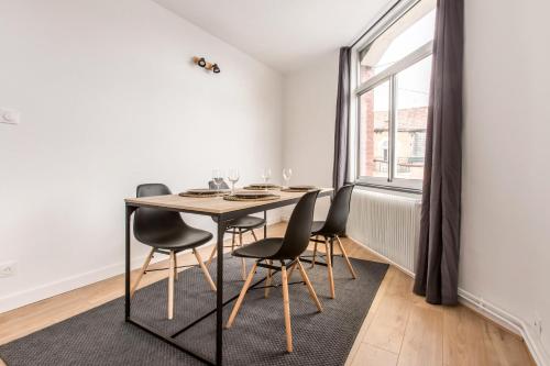 une salle à manger avec une table et des chaises et une fenêtre dans l'établissement Appartement Croisé Laroche 2 (12min de Lille), à Marcq-en-Barœul