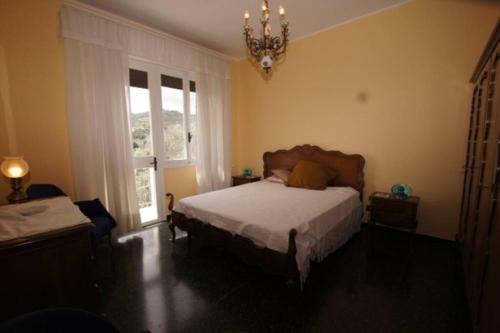 a bedroom with a bed and a window and a chandelier at Casa Belvedere (CITRA 008026-LT-0015) in Diano Castello