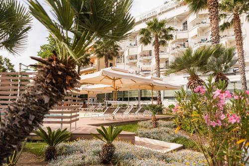 シルヴィ・マリーナにあるHotel Abruzzo Marinaのテーブルと傘、ヤシの木があるホテル