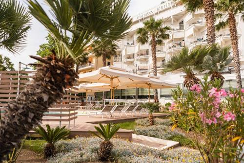 ein Hotel mit Tischen, Sonnenschirmen und Palmen in der Unterkunft Hotel Abruzzo Marina in Silvi Marina