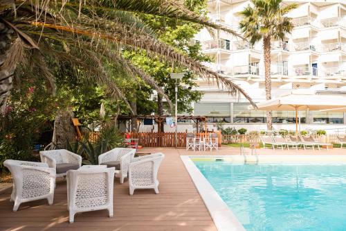 einen Pool mit Stühlen und einem Tisch sowie ein Gebäude in der Unterkunft Hotel Abruzzo Marina in Silvi Marina