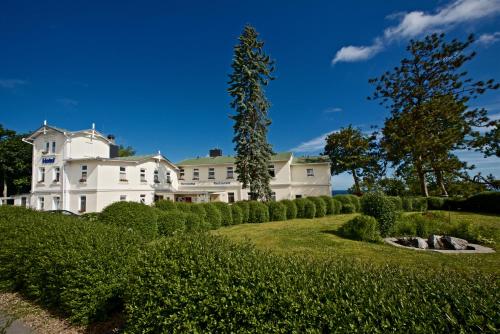 a large white house on a hill with a garden at Panorama Hotel Lohme in Lohme