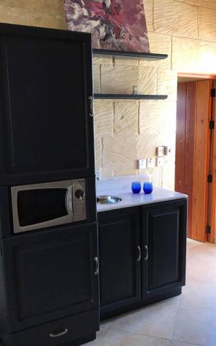 a kitchen with a black cabinet with a microwave at Ta Marie Merhba in Żebbuġ