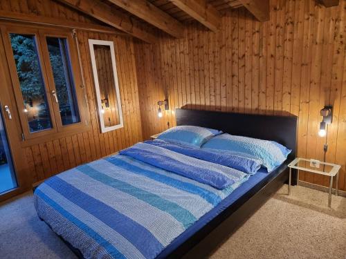 Bett in einem Zimmer mit einer Holzwand in der Unterkunft Half chalet with garden & balcony - 4' to the lake in Laax