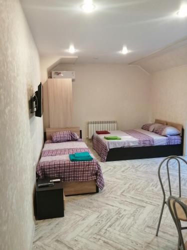 a room with two beds and a table and chairs at Guest House Kamysh in Adler