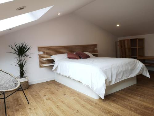 a bedroom with a white bed with a wooden headboard at Cabanela Maitia Apto Telmo Duplex in Ribadeo