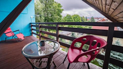 a red chair and a glass table on a balcony at Apartamenty Niebo in Kowary