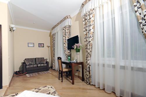 a living room with a couch and a desk with a television at Zolota Forel Hotel in Korostov