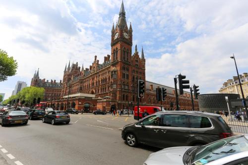 un gran edificio con una torre de reloj y un edificio con coches en The Melville Hotel by Rokxy- Kings Cross, en Londres