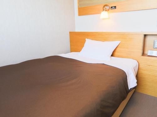 a bedroom with a bed with a brown and white blanket at Castle Inn Sendai in Sendai