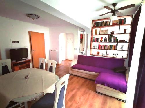 a living room with a purple couch and a table at Apartma Poletje in Koper