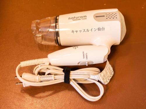 a hair dryer and a bottle on a table at Castle Inn Sendai in Sendai