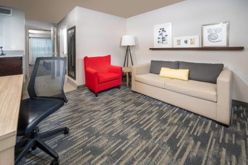 a living room with a couch and a red chair at Country Inn & Suites by Radisson, Rocky Mount, NC in Rocky Mount