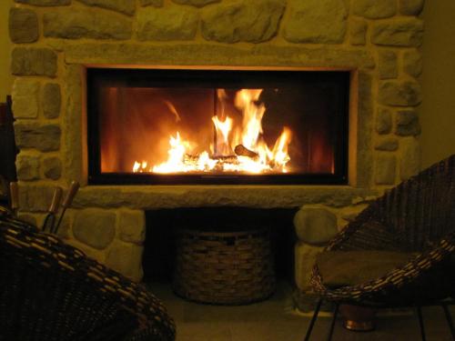 a stone fireplace with two chairs in front of it at Agriturismo La Fontaccia in Rufina